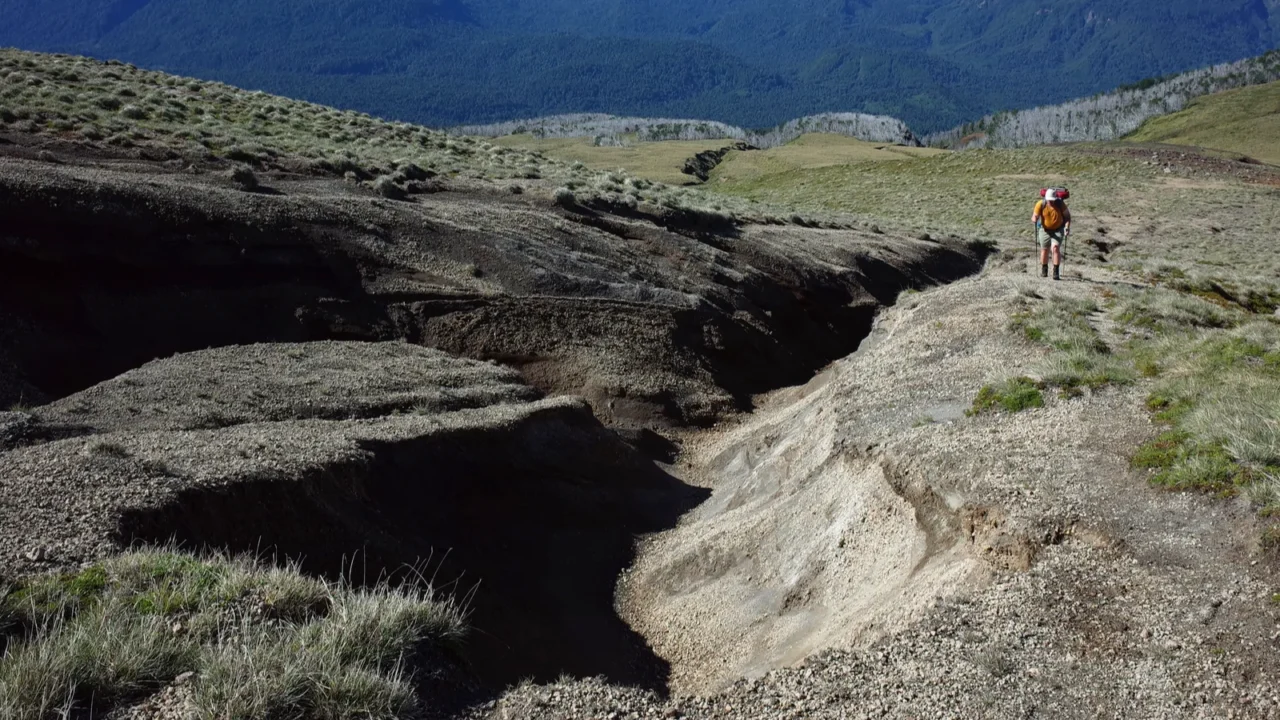 hiking in patagonia man solo walking up mountainside of volcano