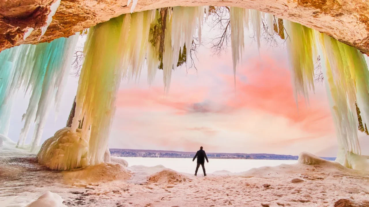human figure silhouette standing in large ice cave entrance during