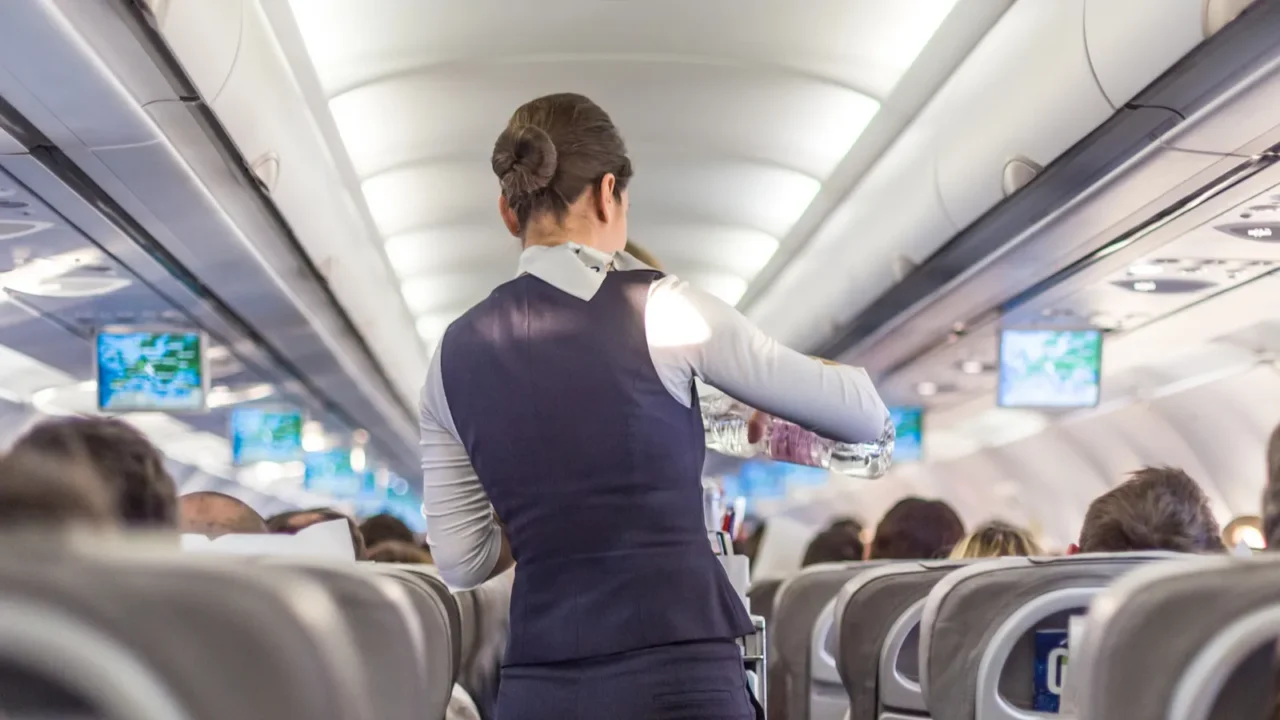 interior of commercial airplane with stewardess serving passengers on seats