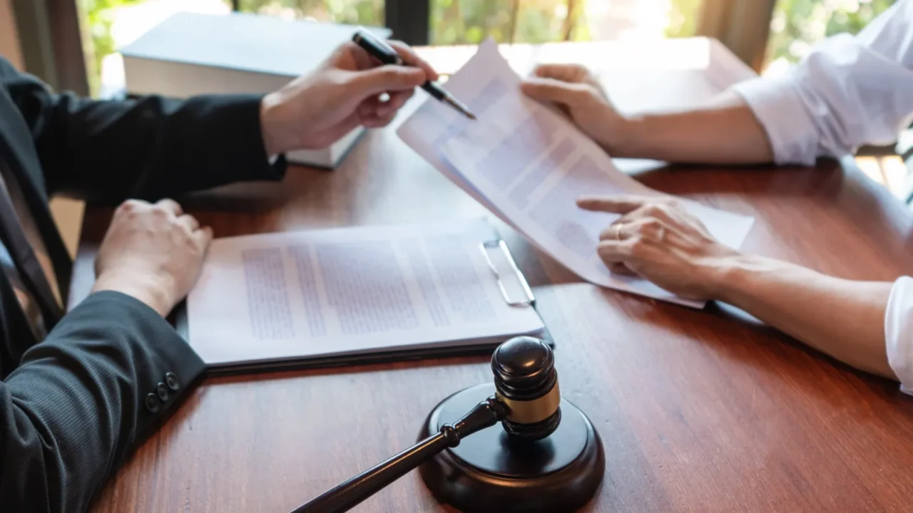 lawyer working with client discussing contract papers with brass scale