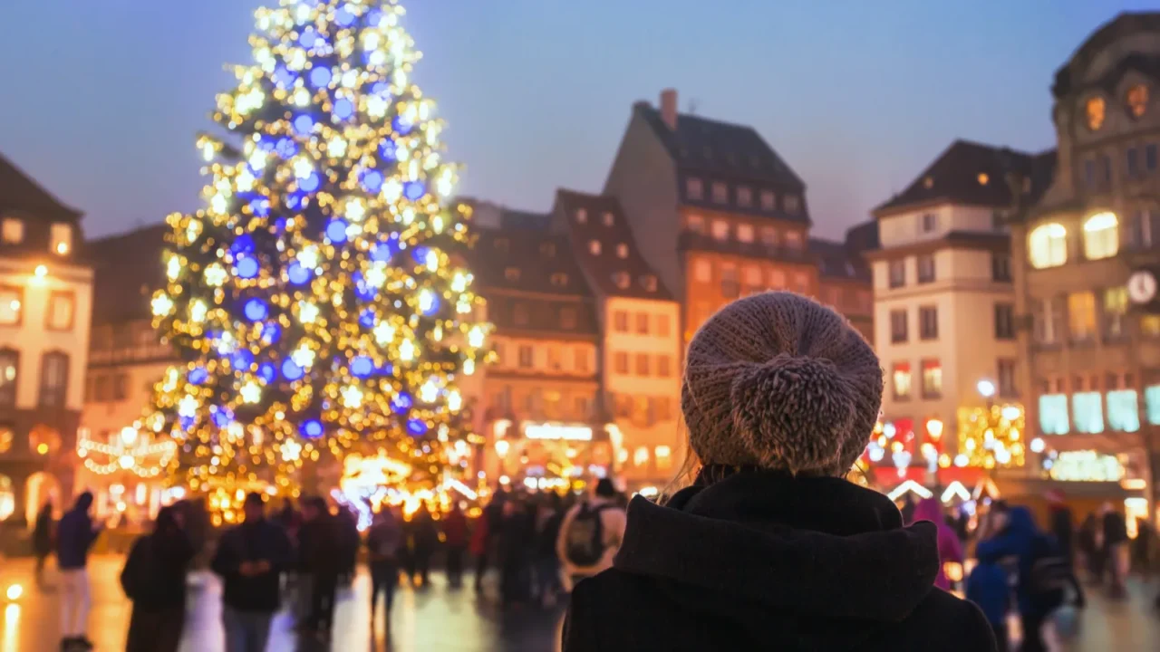 People in the Christmas market, a woman looking at the decorated illuminated tree in Strasbourg, France, Europe.