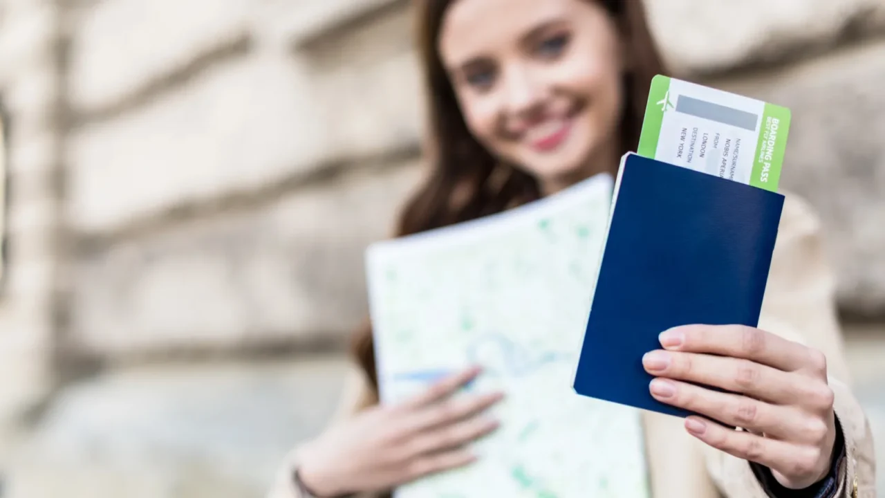 selective focus of woman smiling holding map and showing passport