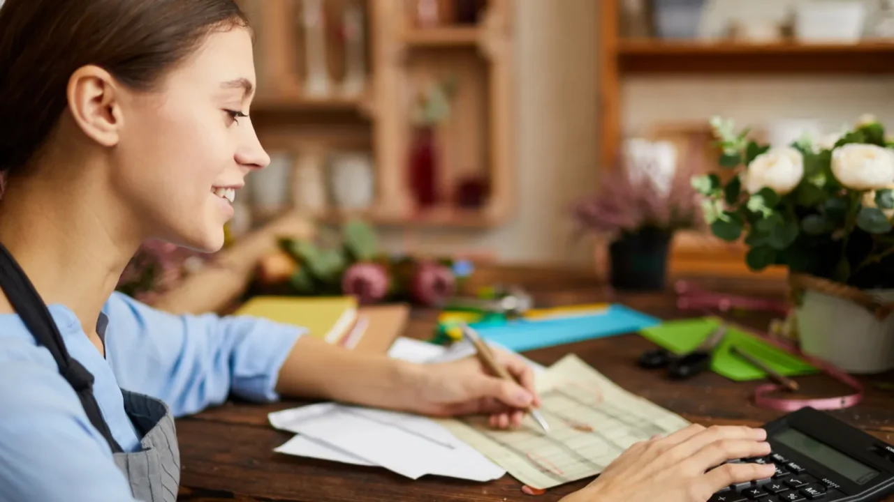 side view portrait of female businesswoman counting finances using calculator