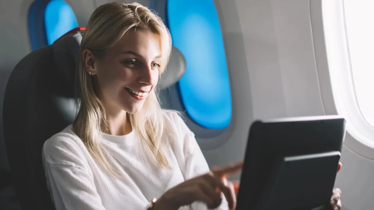 smiling attractive female passenger searching movie to watch on board