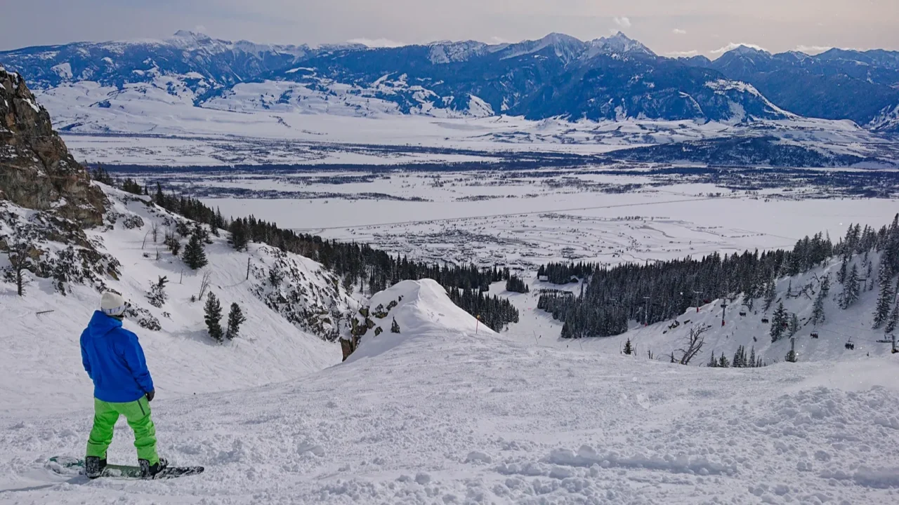 snowboarder observes the snowy landscape before riding down a ski