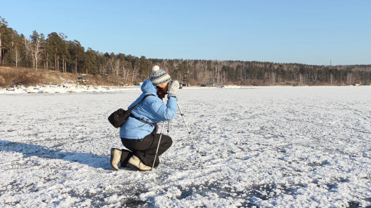 the woman in a blue jacket with a tripod and