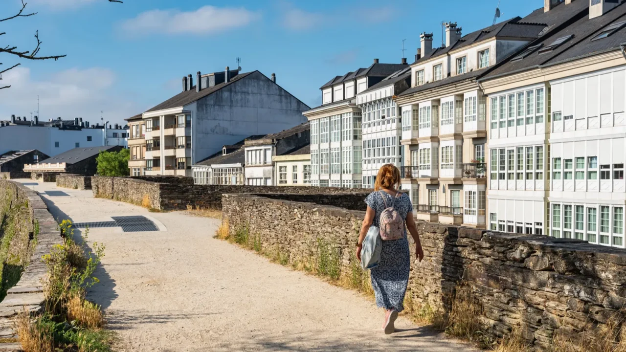 tourist woman with backpack walking over the roman wall that