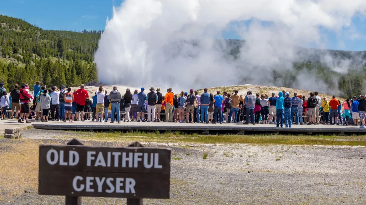 tourists watching the old faithful erupting in yellowstone natio