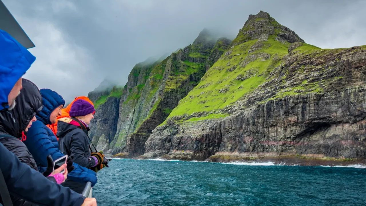 unidentified tourists enjoy de magneficent view of vestmanna cliffs