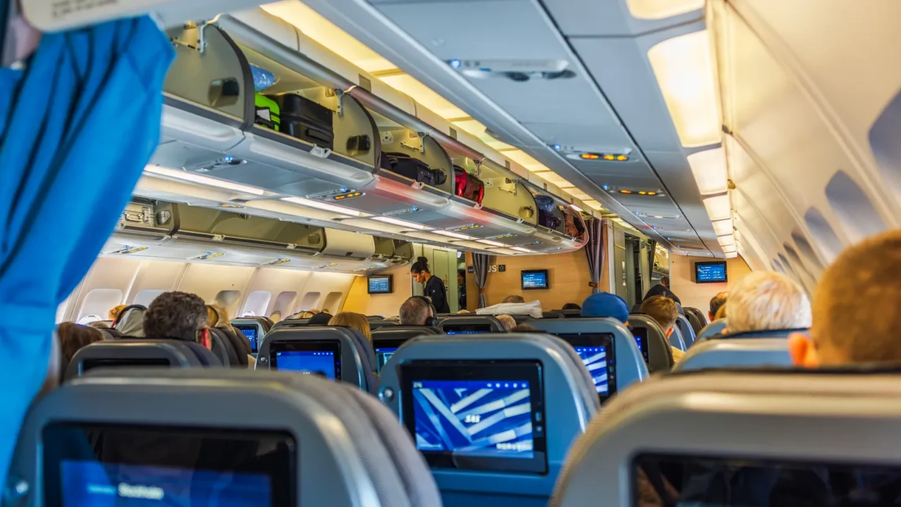 view of airplane economy class cabin showing passengers seated comfortably