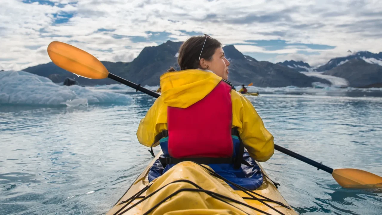 woman paddle a canoe on an icy bay in alaska