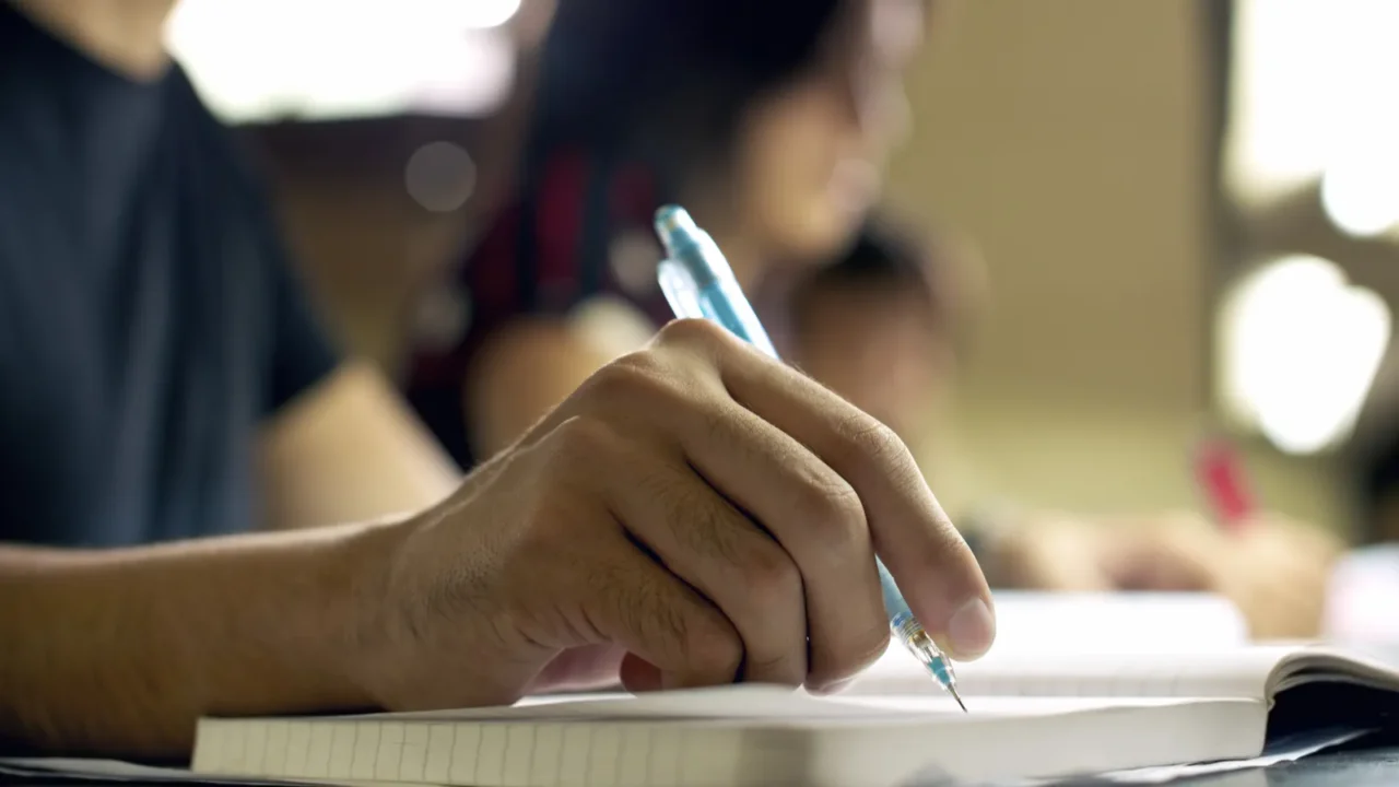 young man doing homework and studying in college library