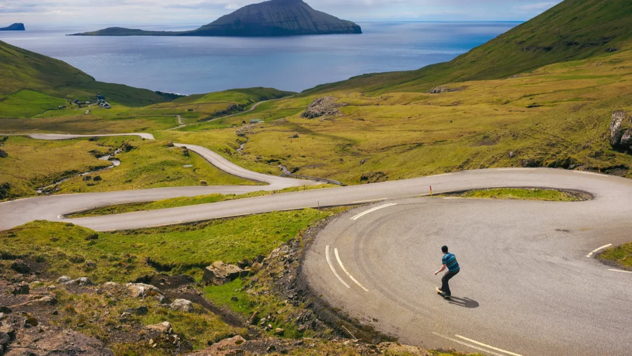 young skater riding a skateboard through beatiful scenery of faroe