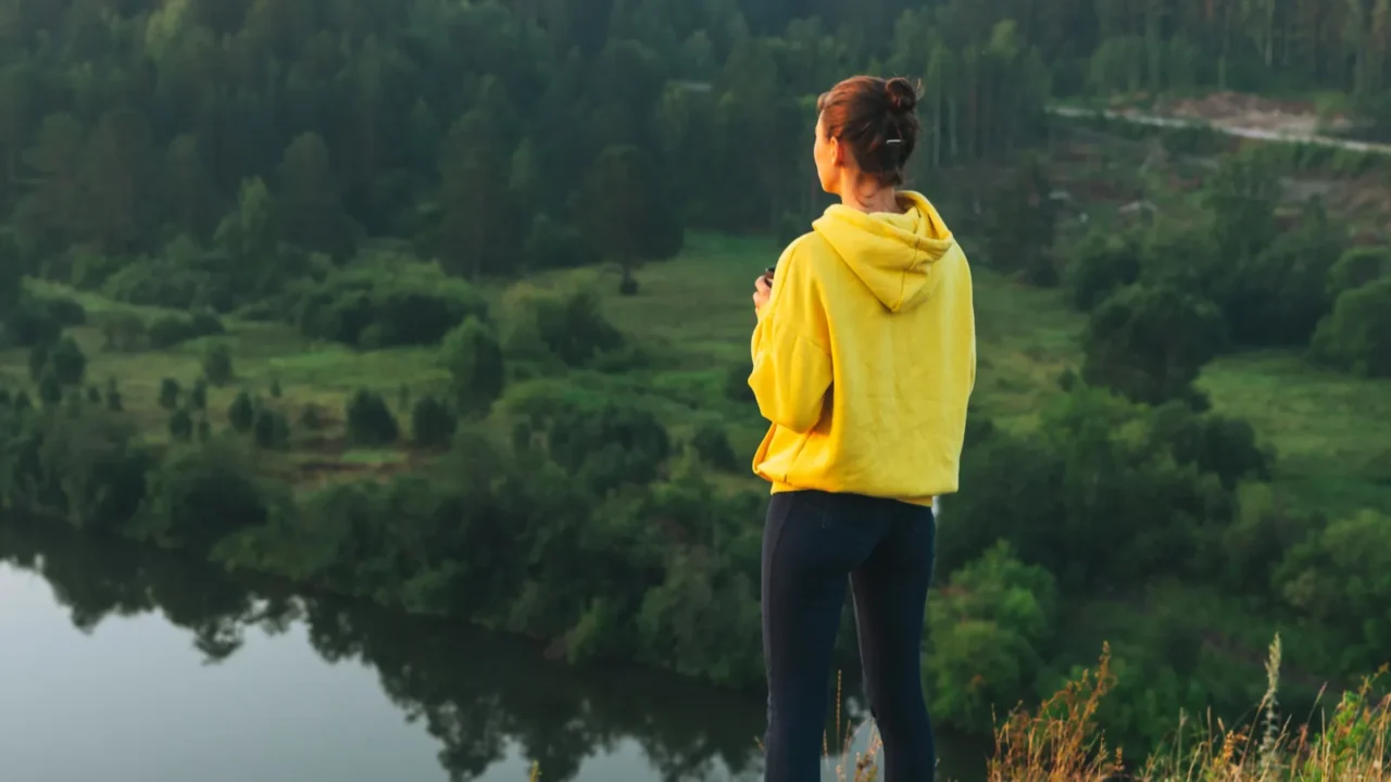 young woman girl traveler in yellow hoodie with cup of