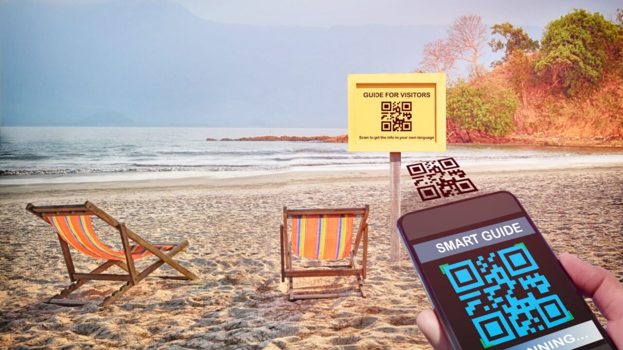 Hand holding smartphone with scanning QR code smart guide screen with guide for visitors sign on tropical beach background. Smart technology concept and qr code quick and easy idea