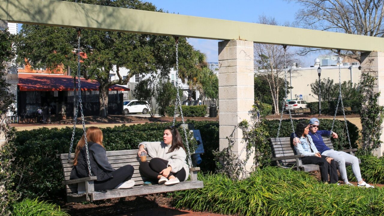 Beaufort, South Carolina, USA - 19 of February 2024: A couple of people relaxing on wood bench swings in Henry Chambers Park Beaufort South Carolina.