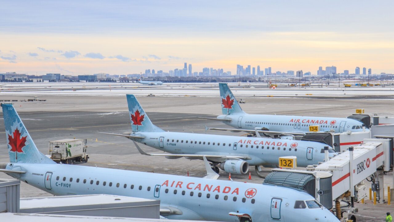 TORONTO, CANADA - JANUARY 8, 2018: Air Canada Embraer 190 regional passenger jets arrive at the terminal building of Toronto Pearson International Airport at dawn. The Toronto skyline is visible.