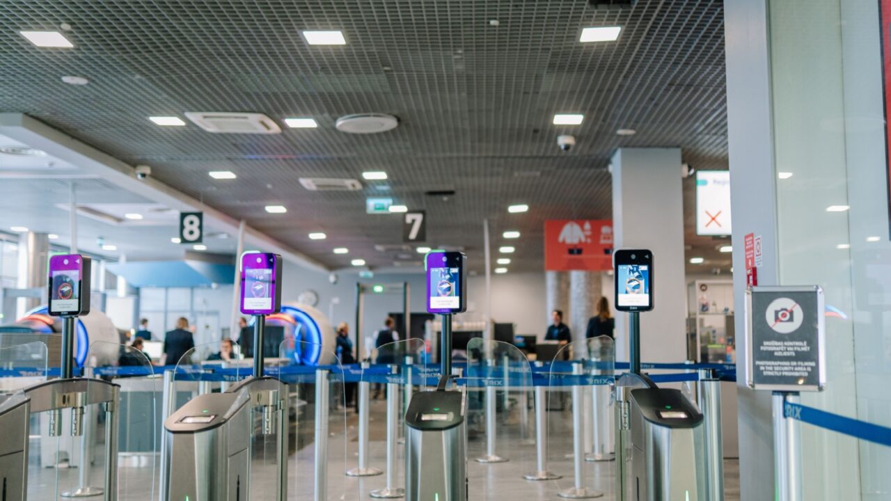 Riga, Latvia - February 22, 2025 - Automated airport security gates with biometric facial recognition scanners. Modern self-check-in area with passengers and staff in the background.