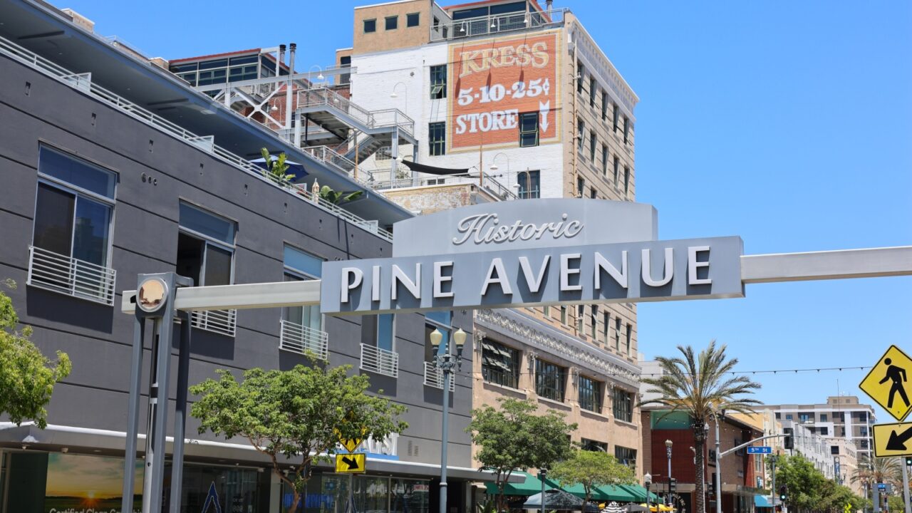 Long Beach, California, USA, July 2, 2025. Pine Avenue Sign Next to Restaurants and Apartments in Downtown Long Beach at The Pike Outlets on a Sunny Summer Day. Next to Shoreline Marina