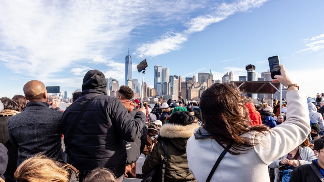 New York City, USA - February 13, 2023 - Tourists taking photos of Manhattan on a ferry from Manhattan to the Statue of Liberty on a winter day