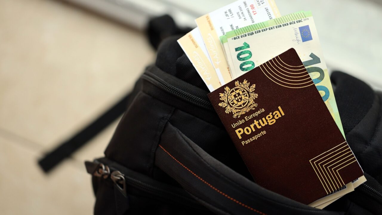 Red Portugal passport of European Union with money and airline tickets on touristic backpack close up. Tourism and travel concept