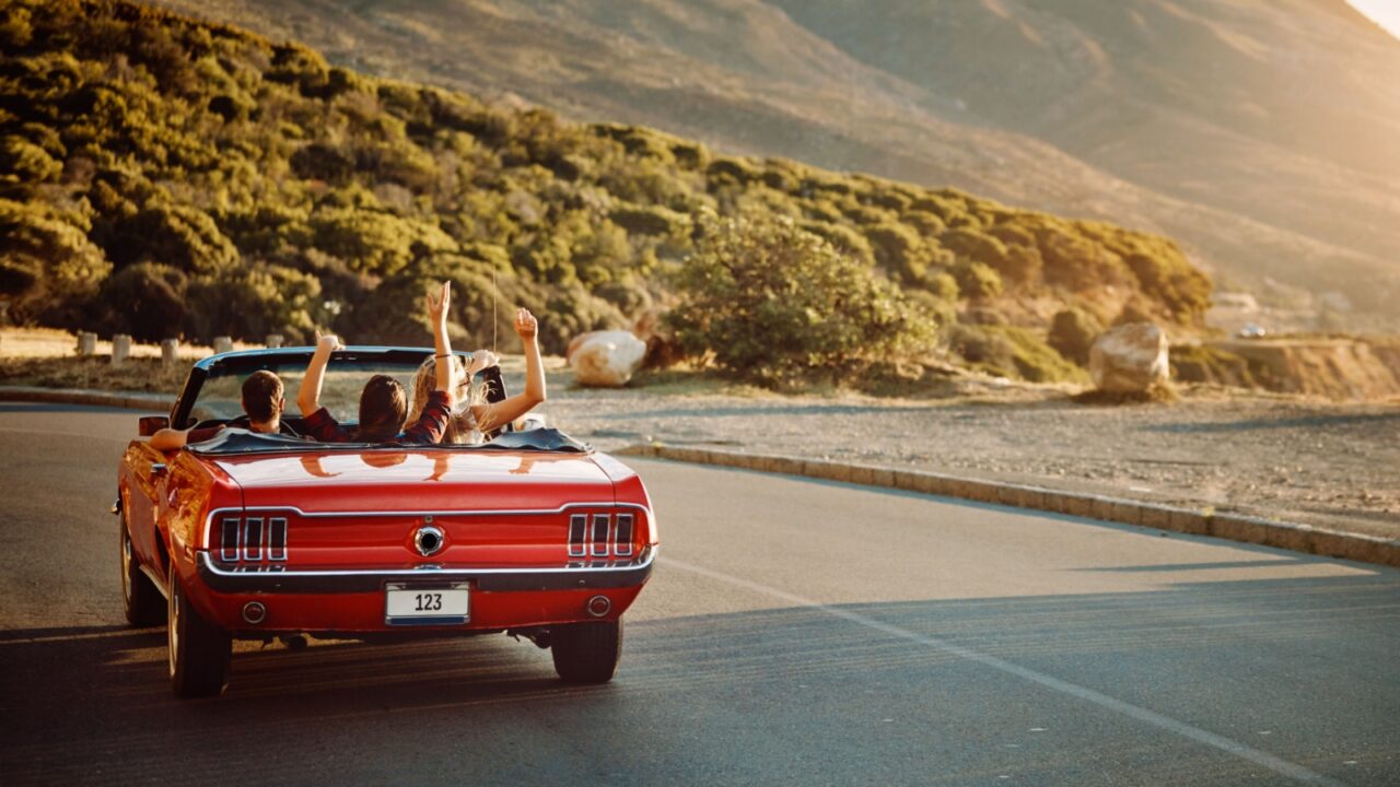 Travel, freedom and friends in car for road trip by sunset for countryside vacation or holiday. Adventure, nature and group of people in convertible for driving to weekend destination in Ireland.