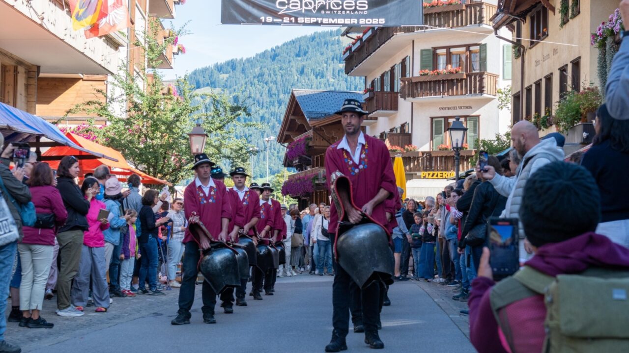 Gstaad, Switzerland - September 6 2025: Traditional cowbell band parades through the alpine town streets, celebrating Swiss culture amid festive spectators and scenic chalets