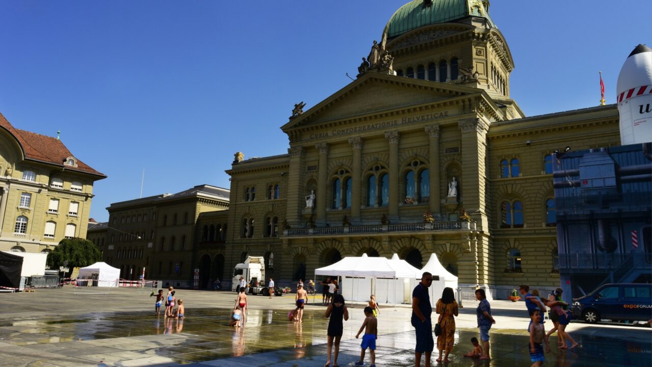 Bern, Switzerland - June 27, 2019: Crowd of people having fun at fountain in front of Parliament Building in Bern, Switzerland