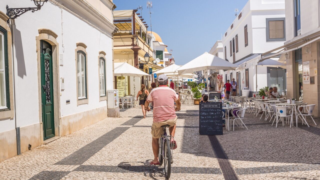 VILA REAL DE SANTO ANTONIO, PORTUGAL - SEP 2 2016. A local man cycles through the cobbled streets in the centre of town. A popular shopping and cafe area for tourists and locals.