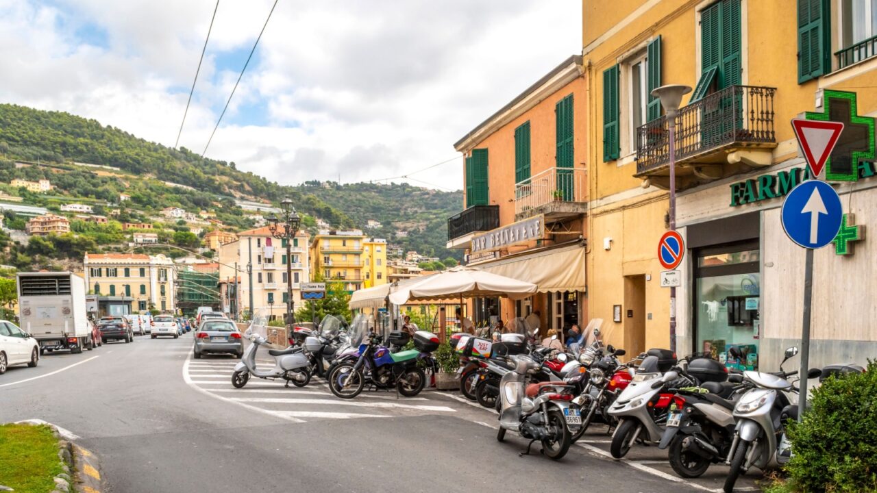 Ventimiglia, Italy - September 28 2019: A large number of scooters, motorcycles and motor bikes park outside a neighborhood bar cafe with patio tables in Ventimiglia, Italy, on the Italian Riviera.