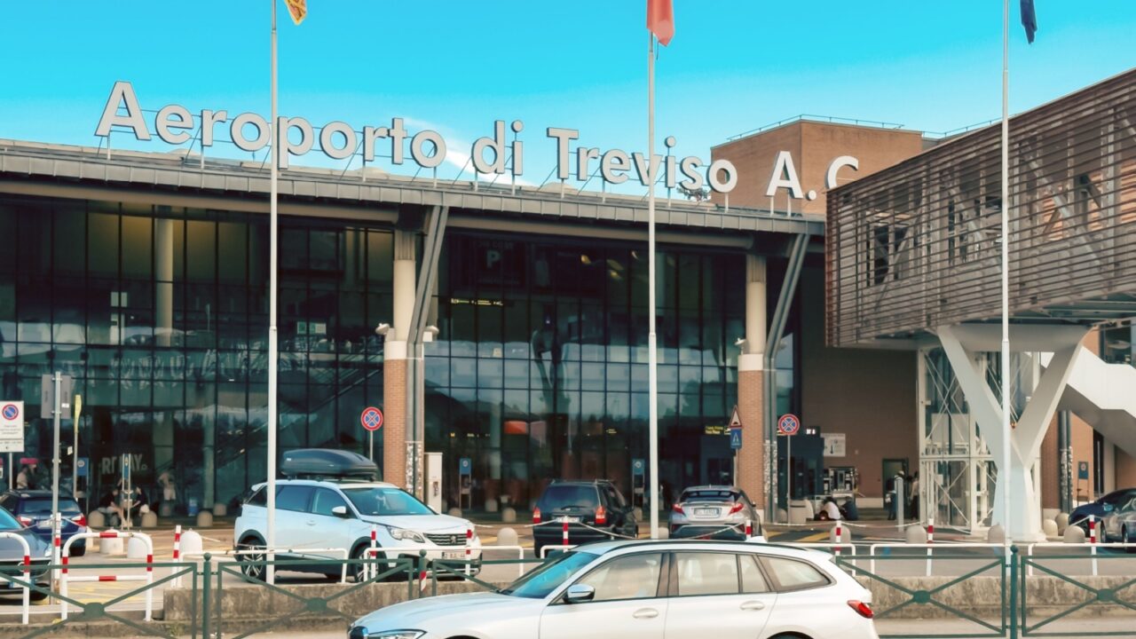07.20.2025, Treviso, Italy – Exterior view of Treviso Airport near Venice with cars, flags, and passengers at entrance