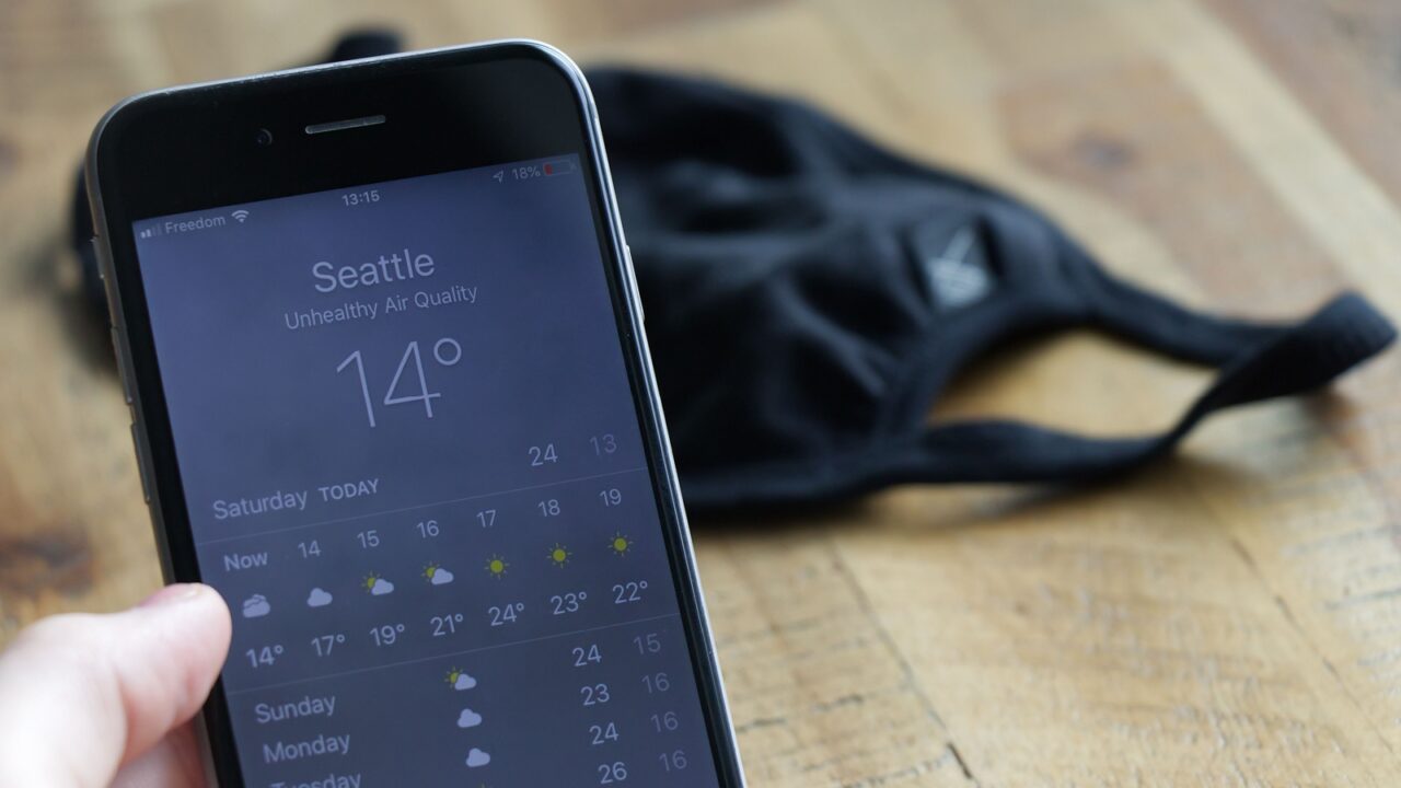 Vancouver,Canada - September 12,2020: View of phone with Weather App which shows Unhealthy Air Quality in Seattle. Face mask in the background