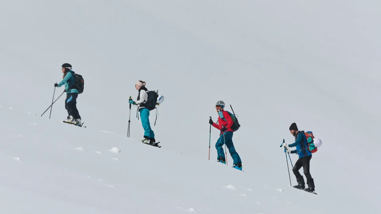 a group of professional ski mountaineers ascend a dangerous snowy