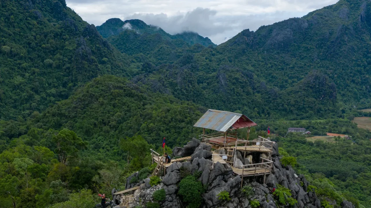 a simple wooden shelter with a metal roof stands atop