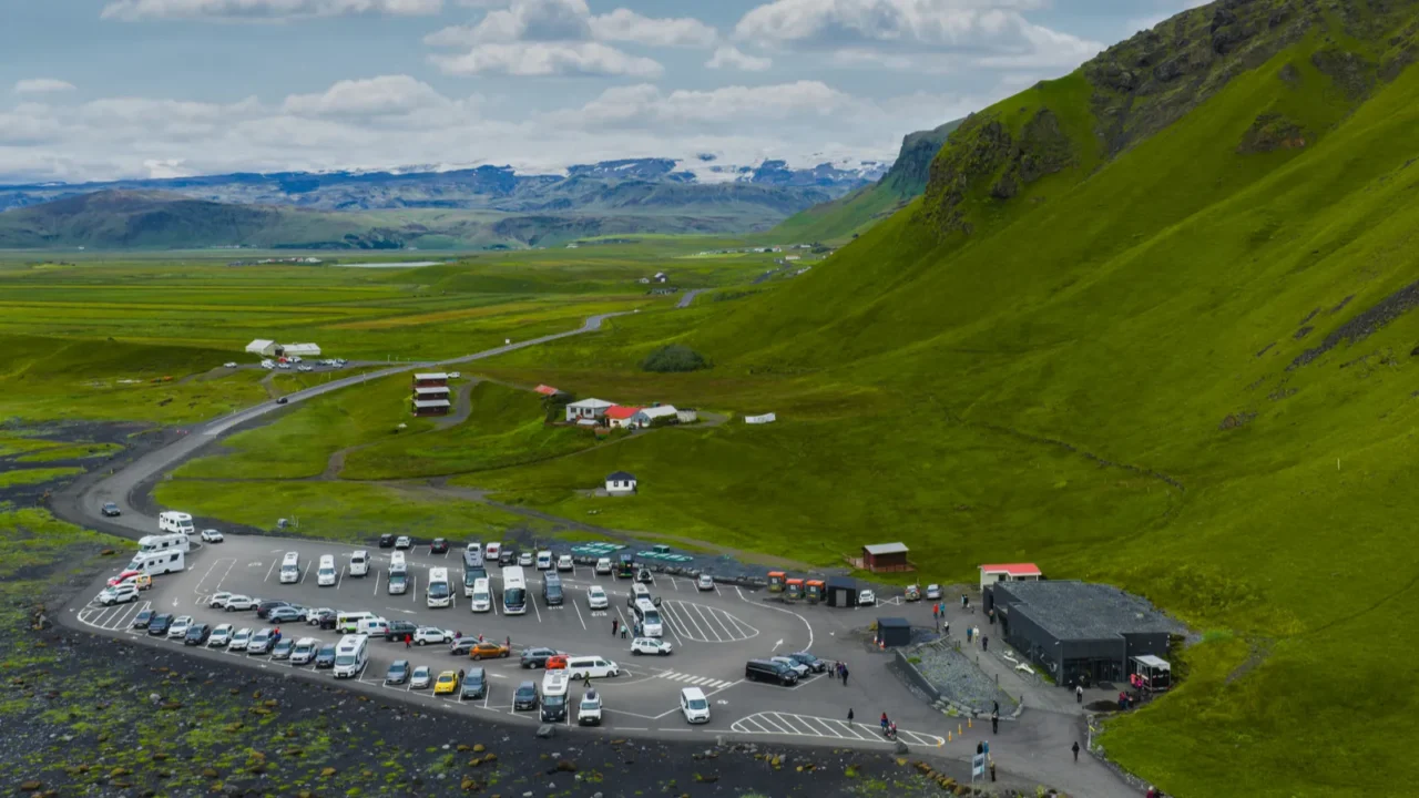 a vibrant green hillside in iceland with a parking lot
