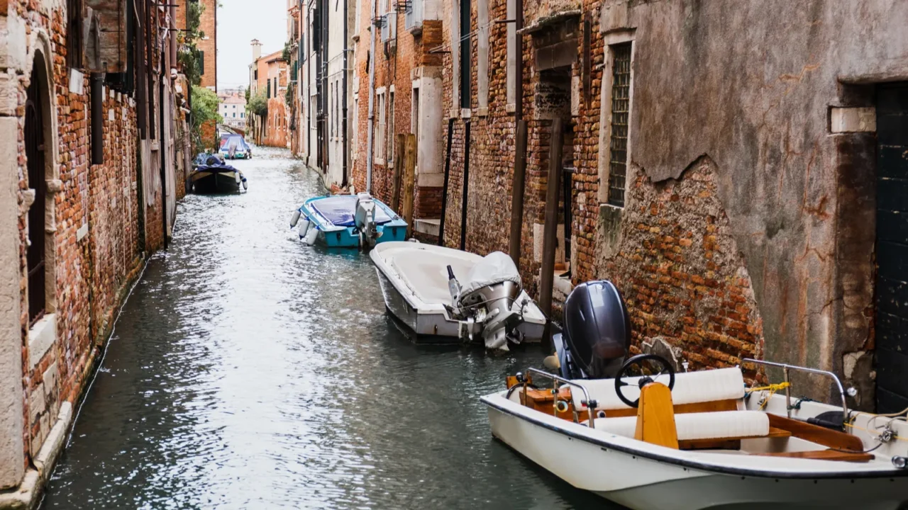 canal motor boats near ancient buildings in venice italy