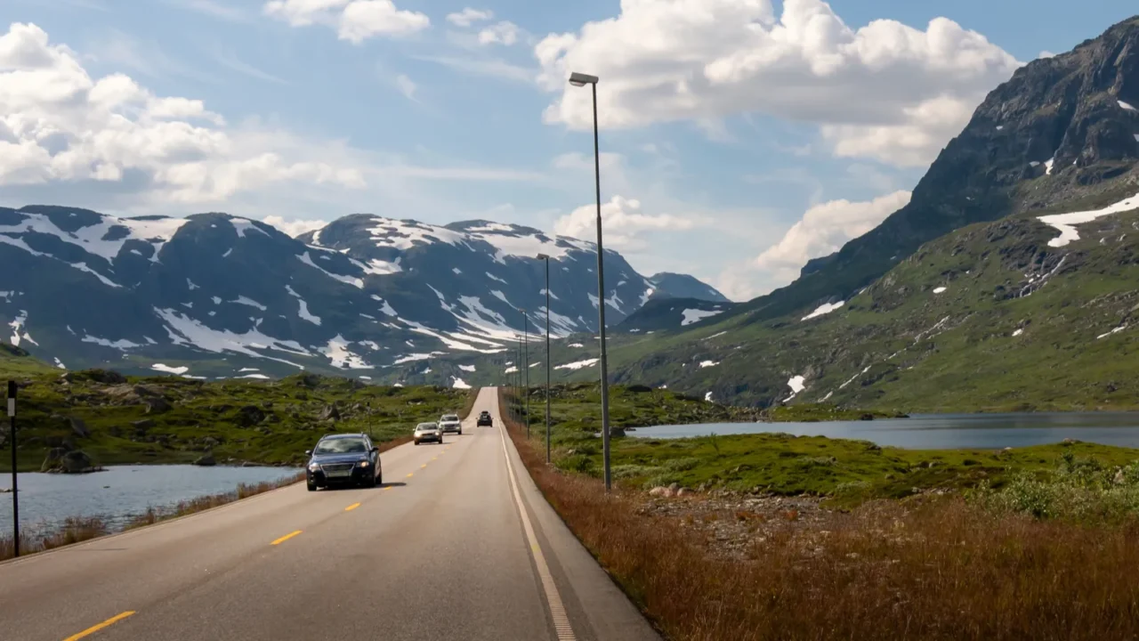 cars travel along a winding road in norway surrounded by