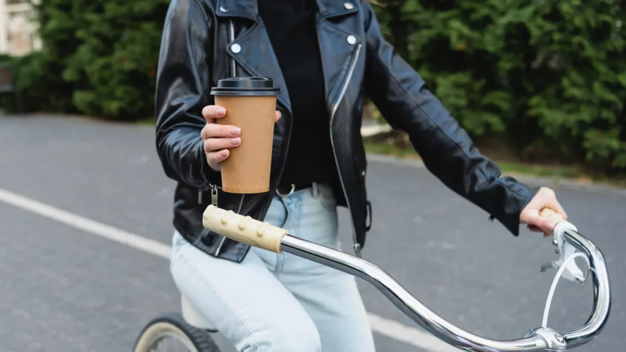 cropped view of happy woman holding paper cup while riding