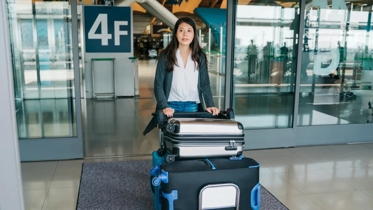 elegant tourist pushing luggage trolley walking out from airport hall