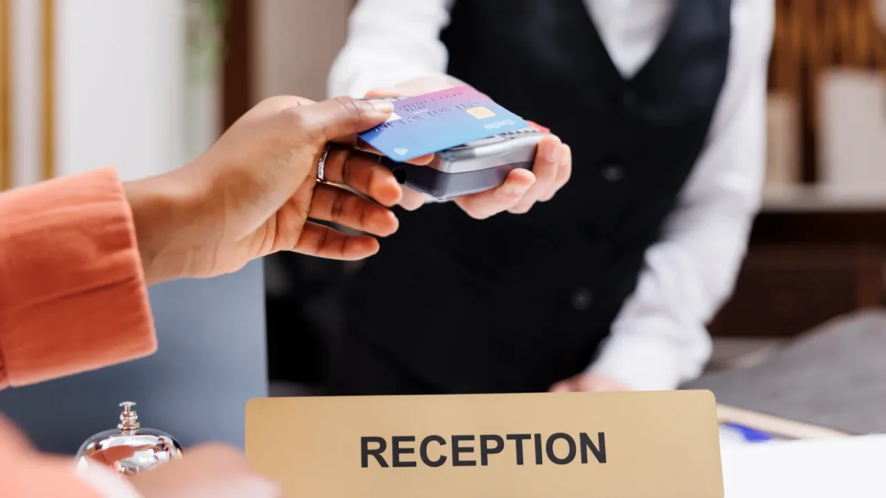 female tourist paying at pos terminal in hotel lobby using