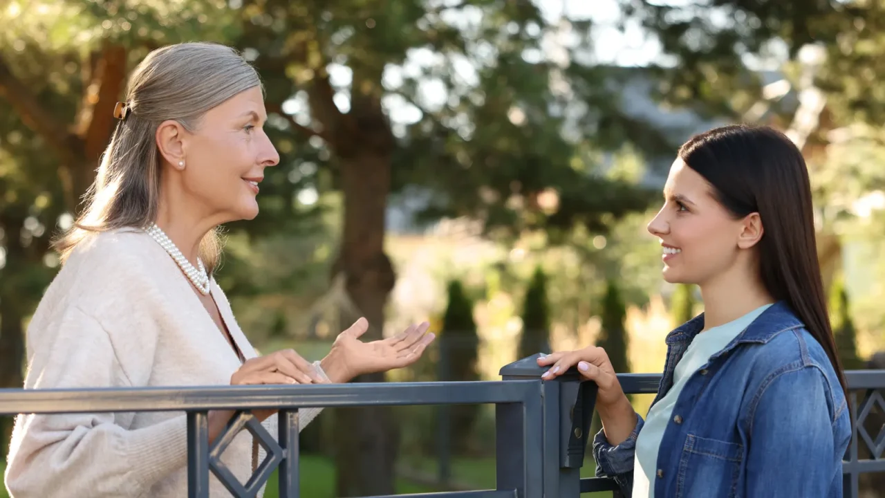 friendly relationship with neighbours happy women talking near fence outdoors