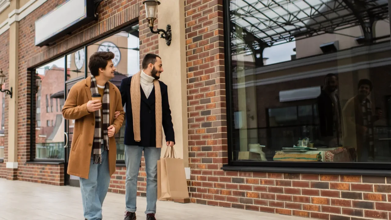 full length of trendy gay men with shopping bags and