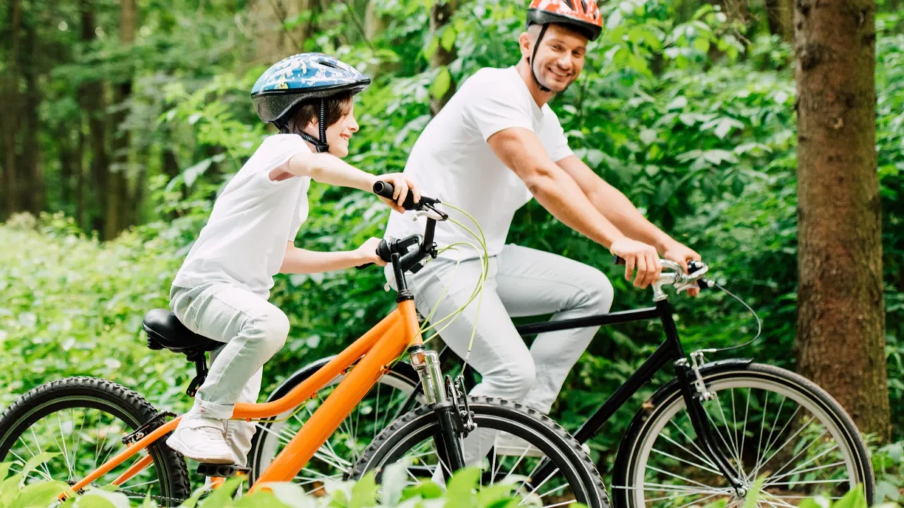 happy father and son smiling while riding bicycles