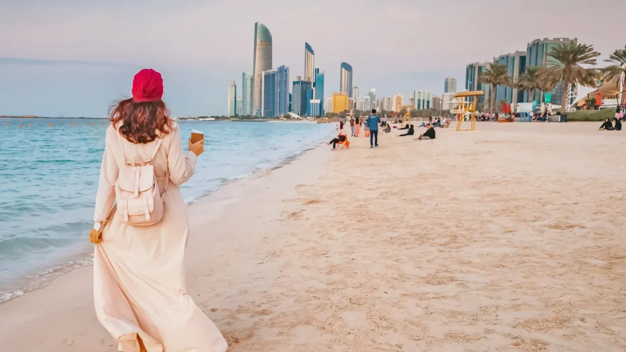 happy girl walking on sandy beach with takeaway coffee with