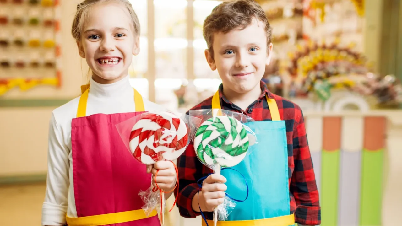 happy little girl and boy holding in hands fresh lollipops
