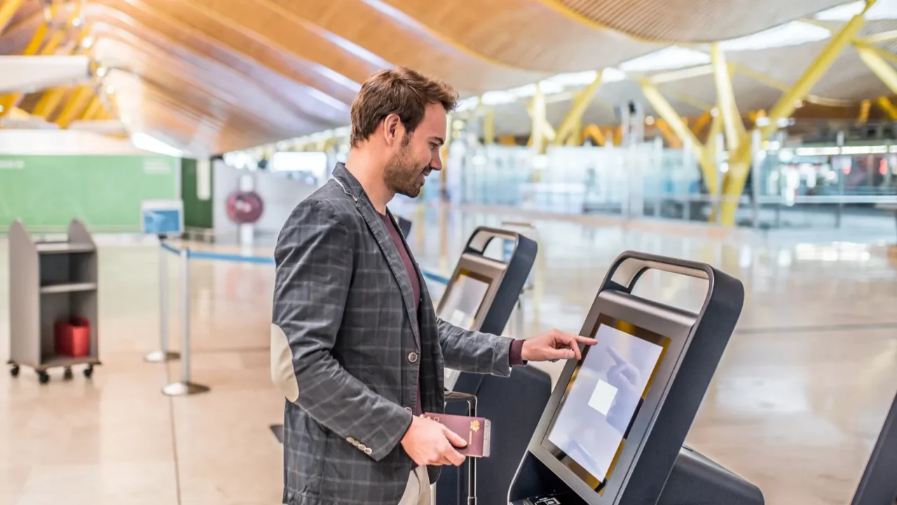 happy man using the checkin machine at the airport getting