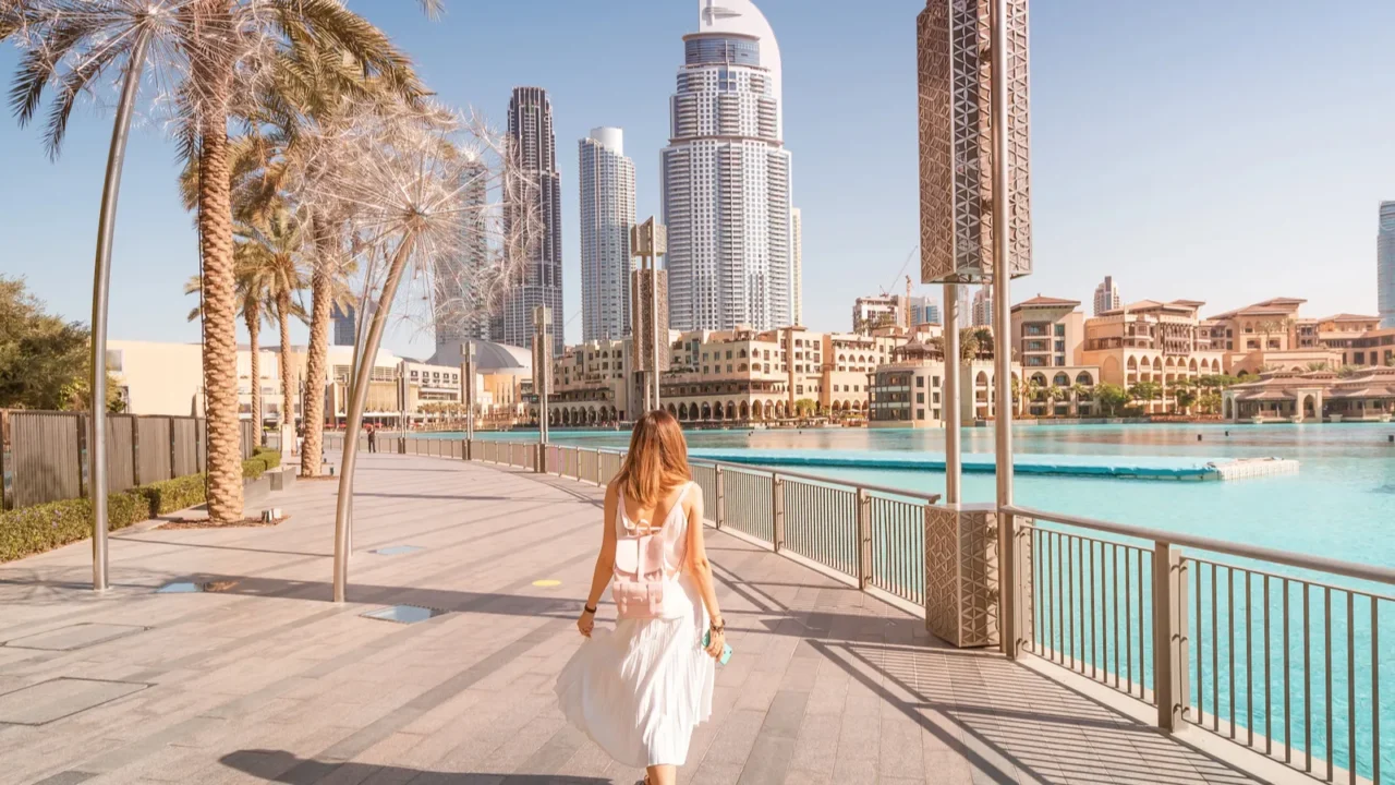 happy tourist girl walking near fountains in dubai city vacation