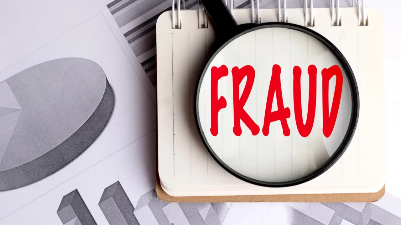 magnifying glass highlighting the word fraud on notebook with financial