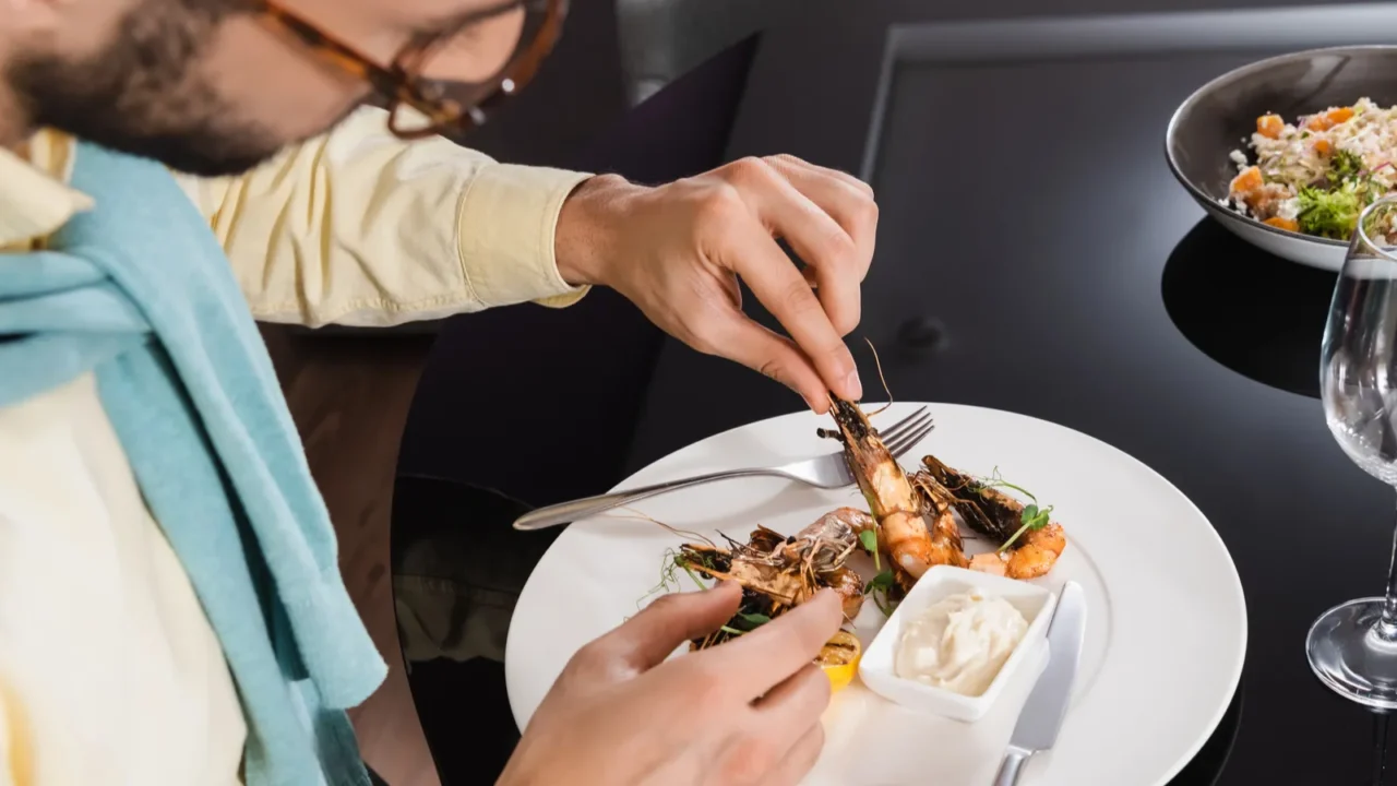 muslim man sitting near tasty shrimps and water on table