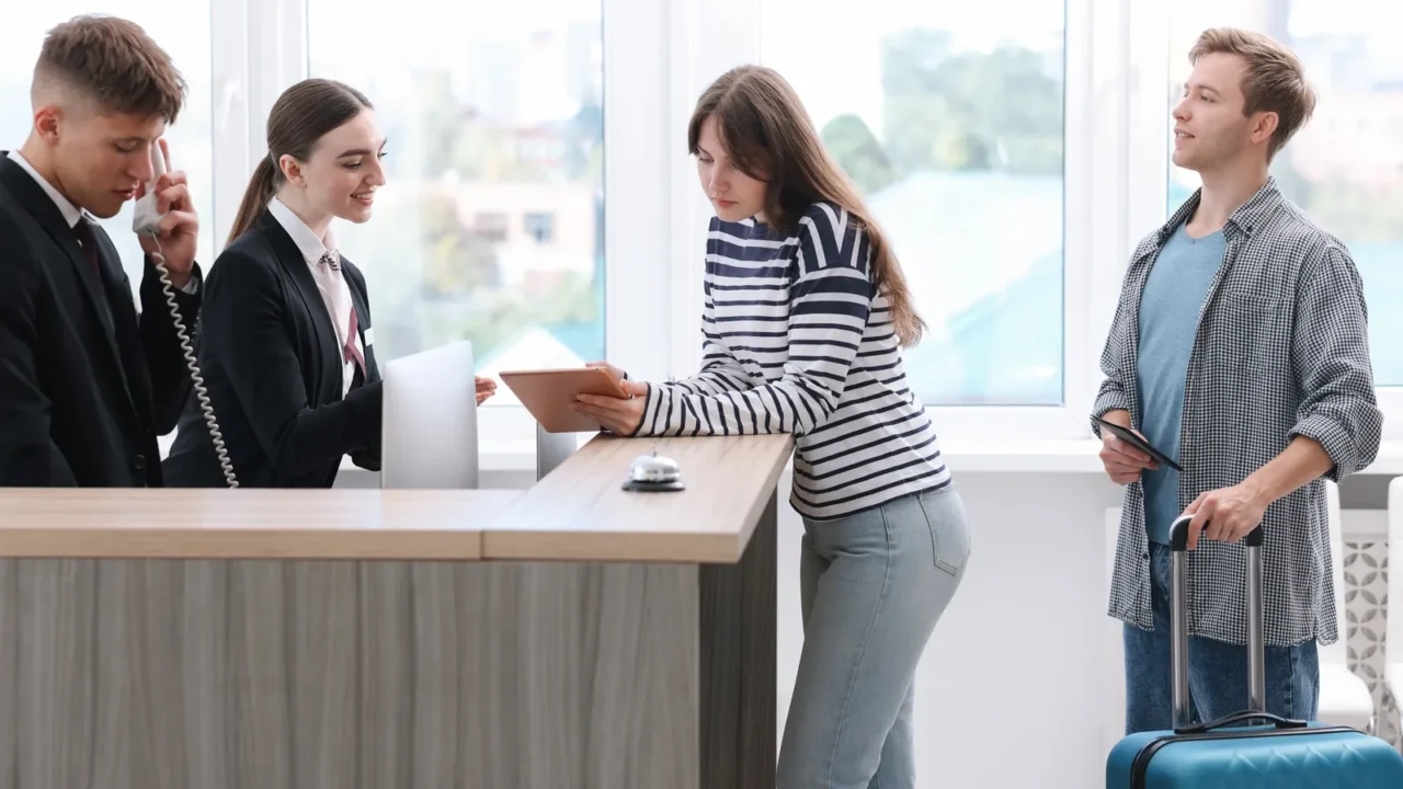 receptionist and hostess working with guests at reception desk in
